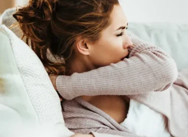 Mujer acostada en la cama y tosiendo en el hueco del brazo - Tos peor por la noche y en la cama: por qué los síntomas del asma empeoran por la noche